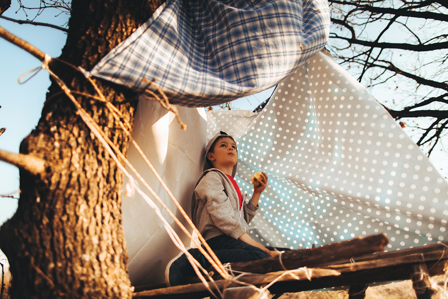 boy in a tree shelter with blankets