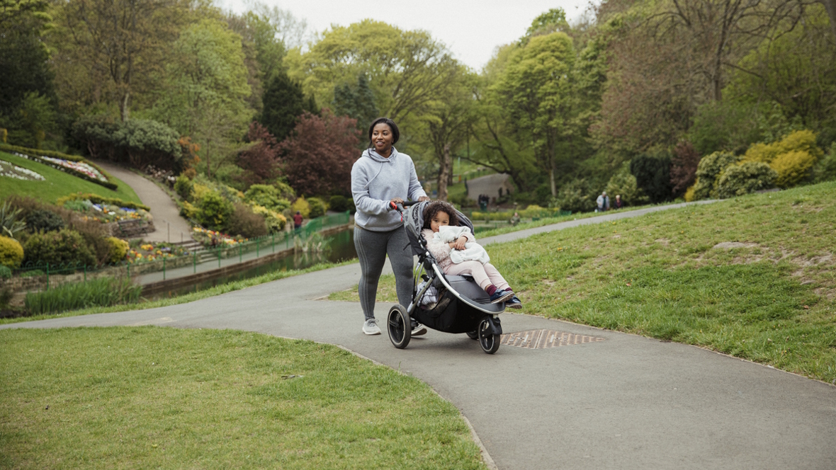 mom pushing a stroller down a park path