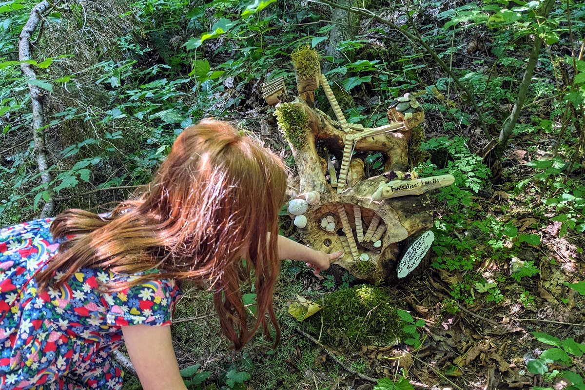 At the Sammamish Fairy House Trail by Beaver Lake, a girl points to a fairy home
