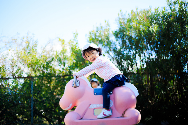 child rides a horse toy at a playground in an Olympics-inspired game