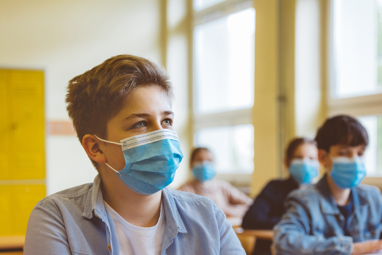 High school students wearing N95 face masks sit in a classroom