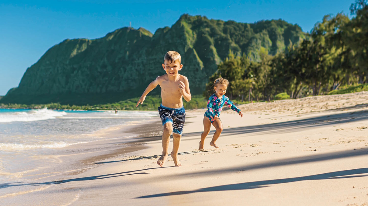 Two kids running on a beach Kauai family vacation things to do