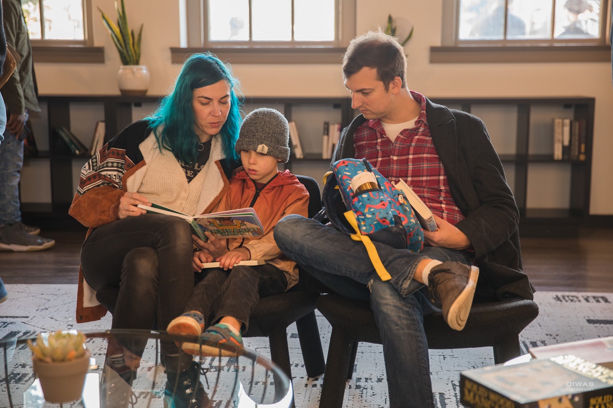 A family looks at a book in the Northwest African American Museum’s living room style space