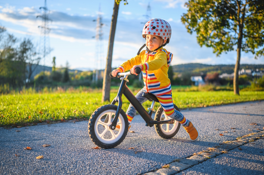 a young boy riding a balance bike teach your kids to ride a bike