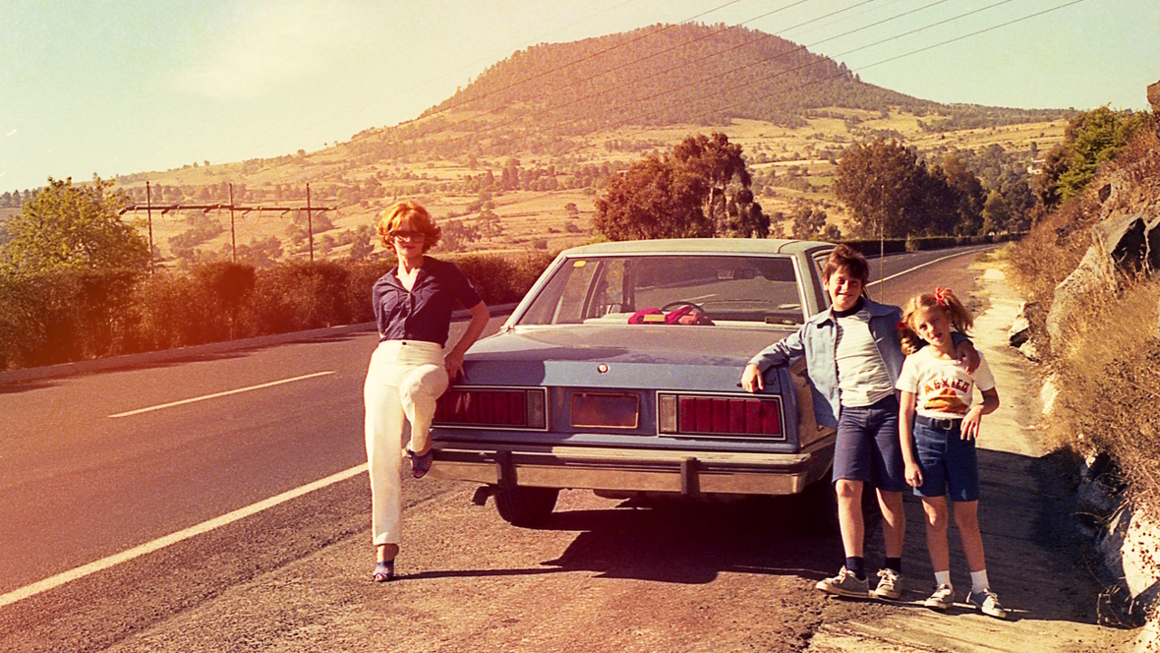 Vintage photo of a family standing next to a car on a county road