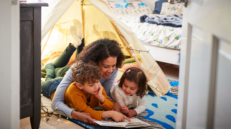 Mom reading with two kids on the floor of their bedroom Passover books