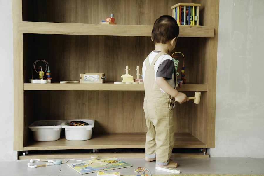 child takes toys from a low shelf, showing the value of accessibility in Montessori playrooms