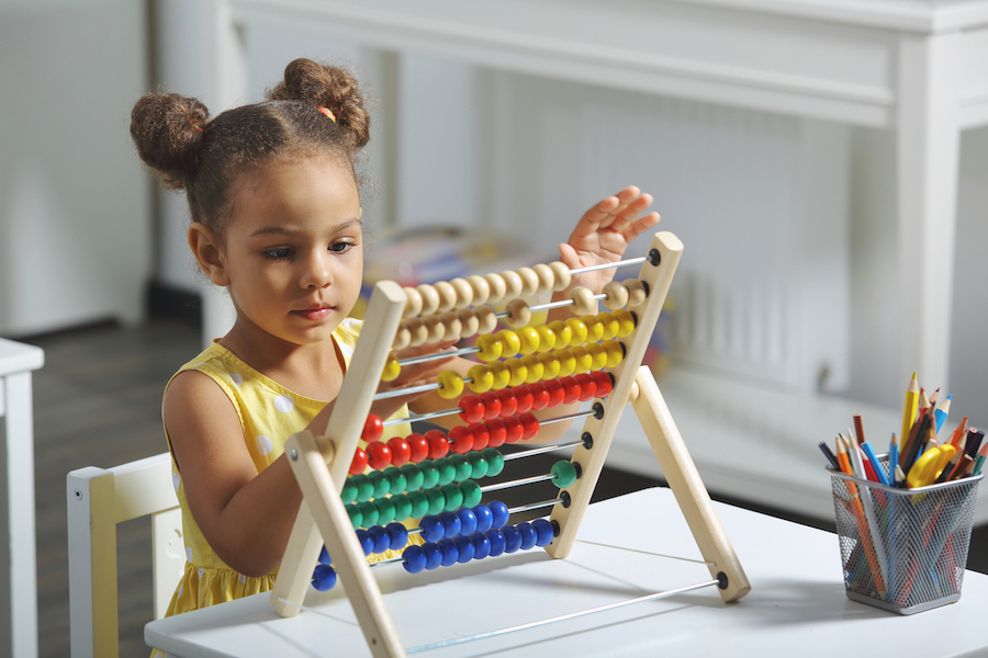 a child plays with an abacus, encouraging purposeful engagement in a Montessori playroom
