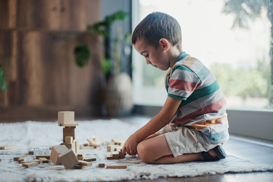 a child plays with simple wood blocks in a Montessori playroom