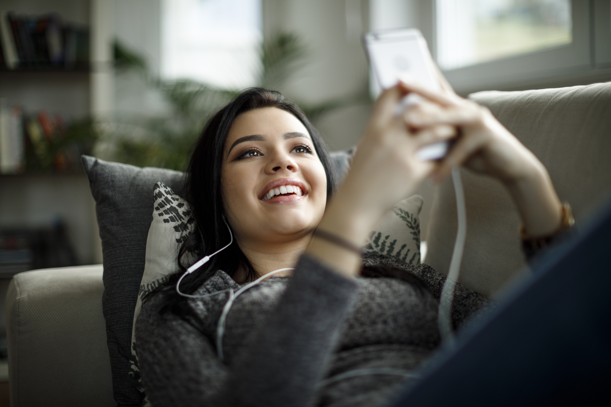 teen girl laying on the couch looking at her phone