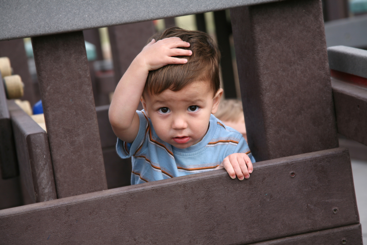 toddler holding his head on a play structure