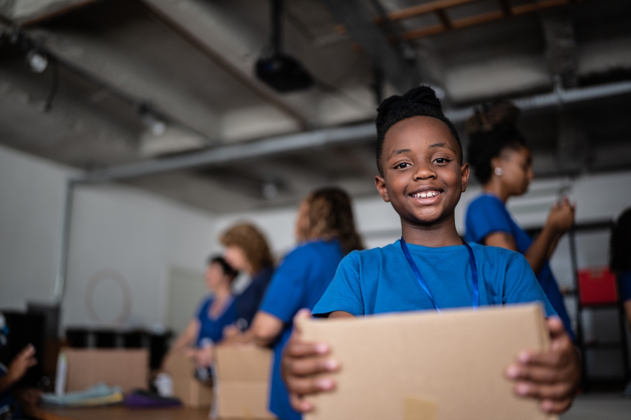 Young boy holding a box and volunteering at a community center