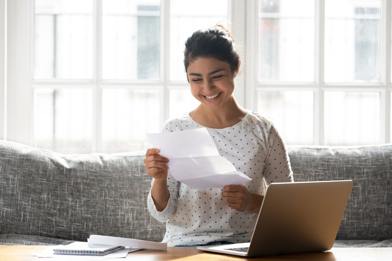 Happy young woman holding a letter reading good news about her college admission