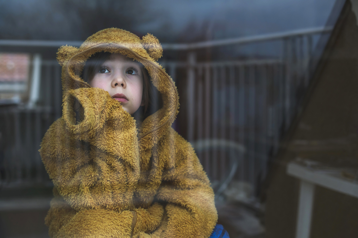 child experiencing winter burnout looking out a window