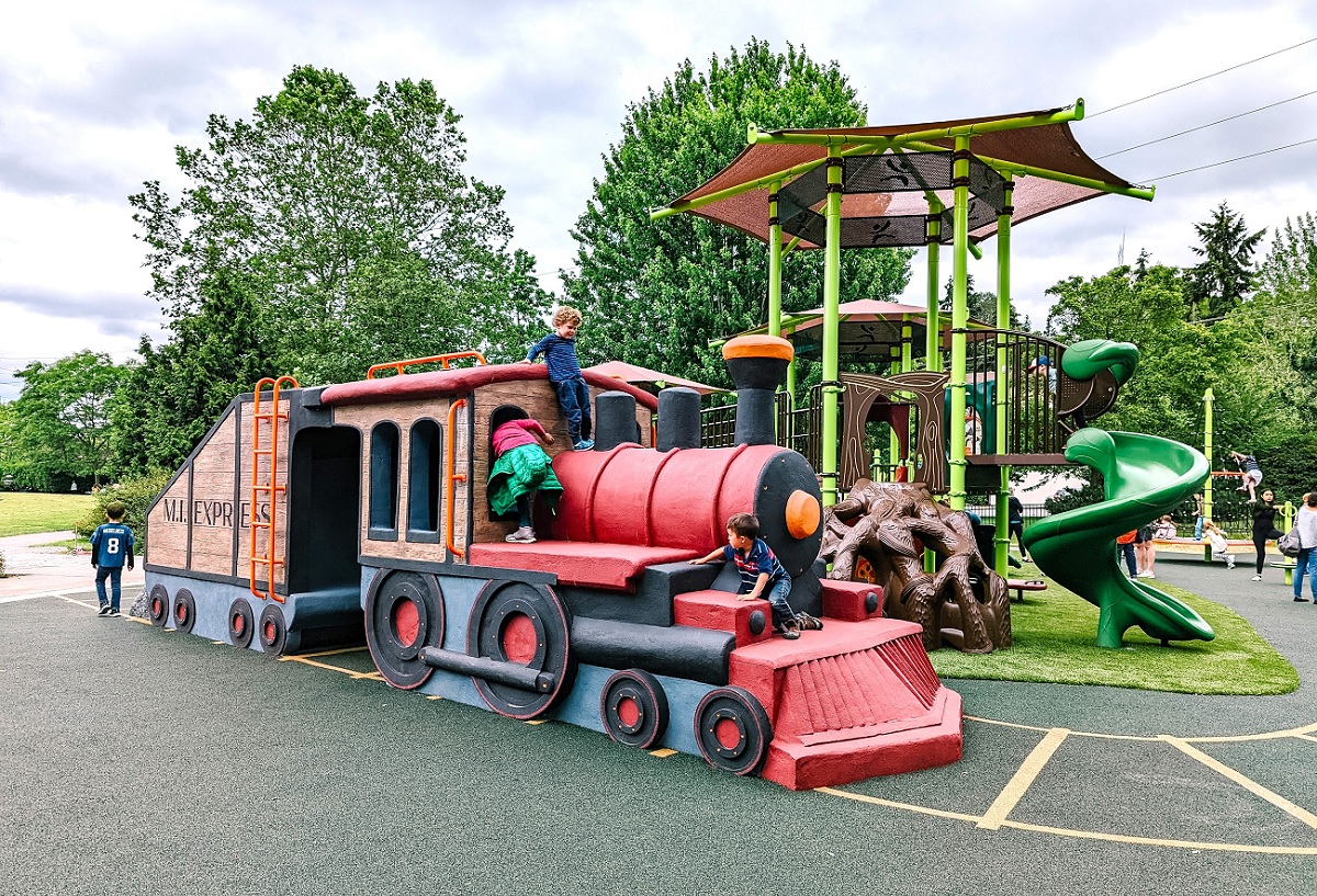 Playground train with children climbing on it at Mercerdale Park on Mercer Island, the playground is known as train park