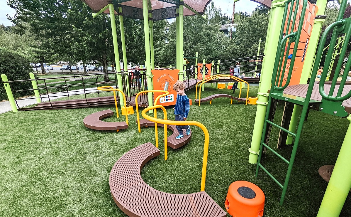 A young boy plays on the curved pathway balance elements at the new Train Park playground at Mercer Island's Mercerdale Park near Seattle