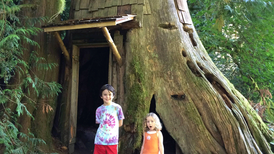 Two kids stand in front of the stump house at Guillemot Cove Nature Reserve