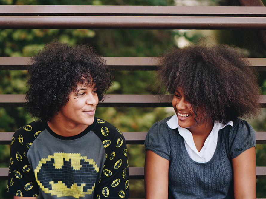 siblings side by side smiling at each other outside