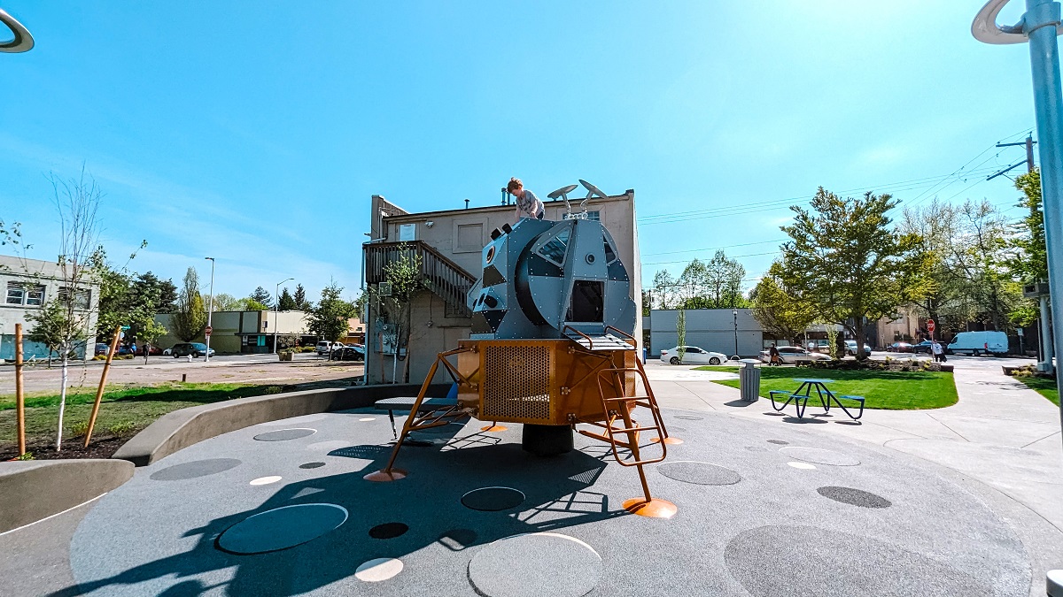 A boy perches on the very top of the lunar lander replica play structure at Kent's new Kherson Park playground