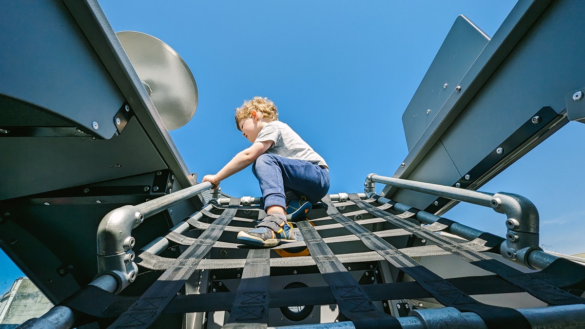 A boy climbs a cargo net to the lunar lander at Kent's Kherson Park playground