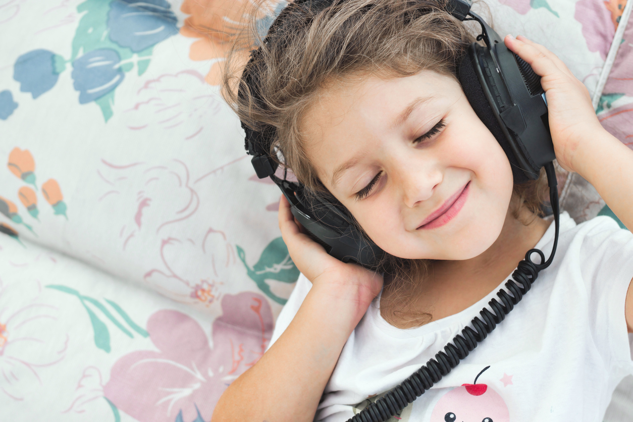 a child wears headphones while happily listening to music from a goody bag CD