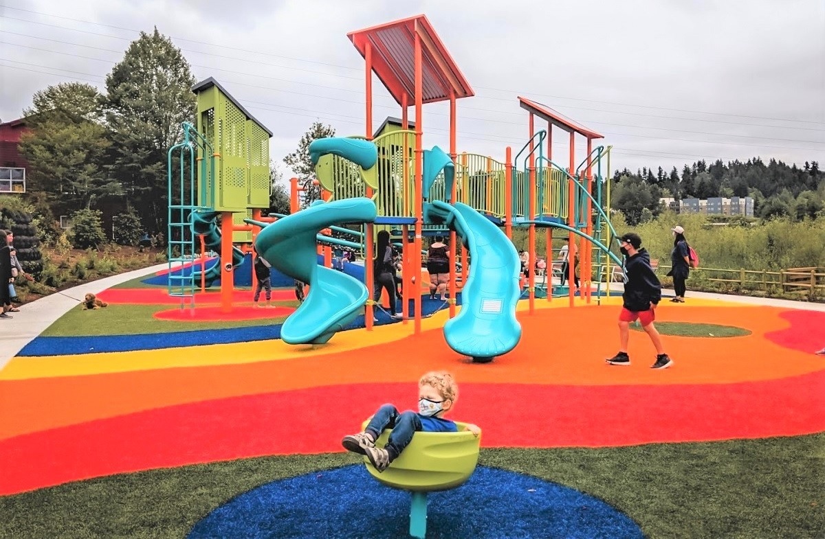 boy in a teacup play fixture with a colorful turf playground in the background at totem lake playground