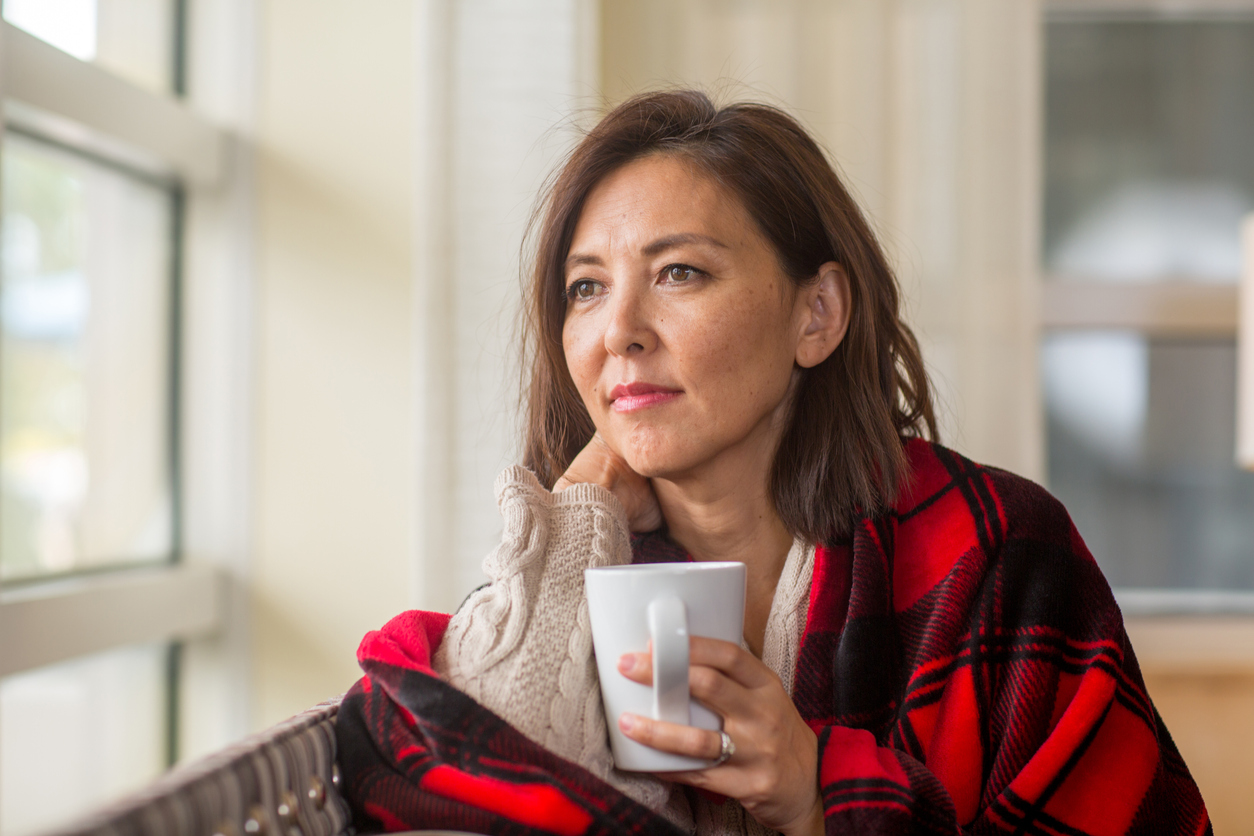 Mature woman looking out of the window, feeling sad