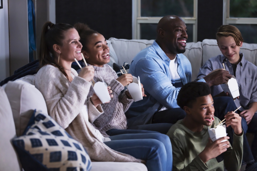 Family watching TV and eating takeout