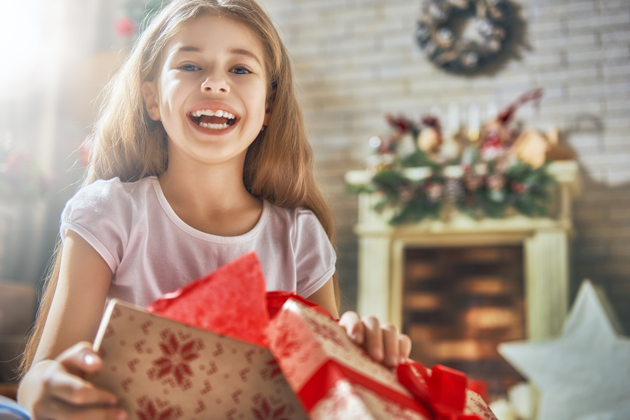 girl opening a gift with a fireplace in the background