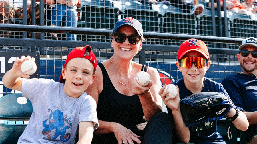 family holding baseballs at a Tacoma Rainiers baseball game, an affordable sports outing for families
