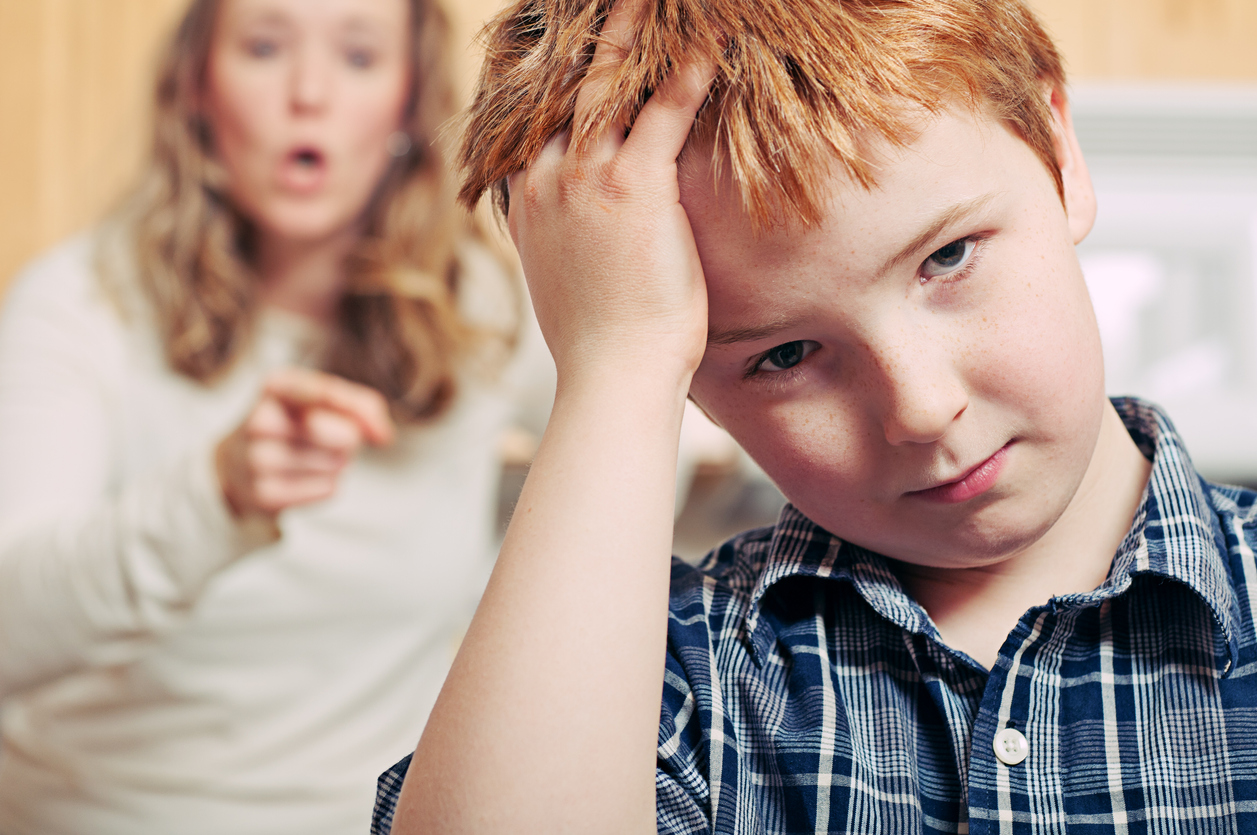 Exasperated young boy being scolded by his mother
