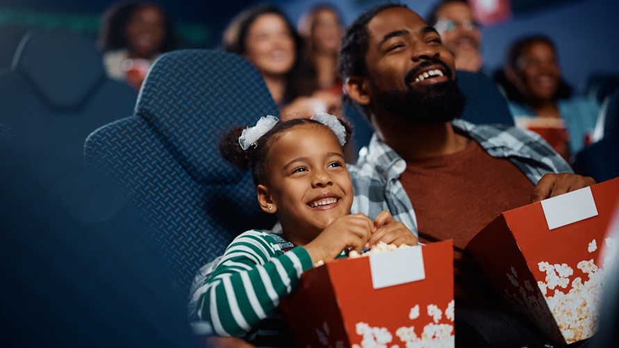 Dad and daughter at a movie eating popcorn one on one time together