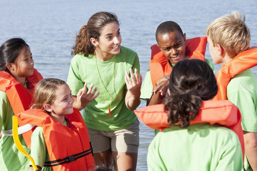 A teen girl with younger children all wearing life jackets is a great leadership experience outdoors