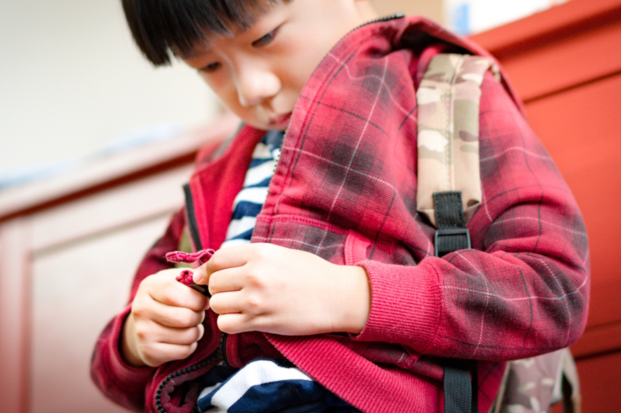 Child practicing zipping up his jacket