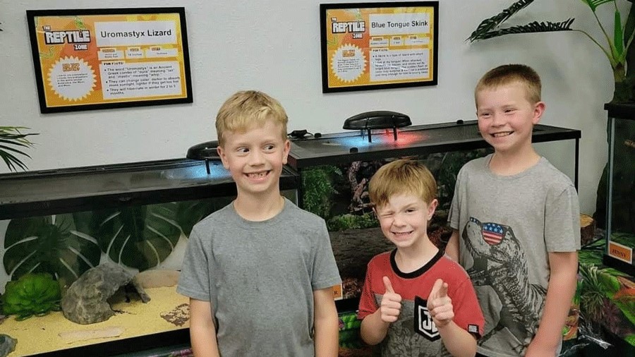 Kids smiling in front of the reptile exhibit at the Bug & Reptile Museum in Bremerton