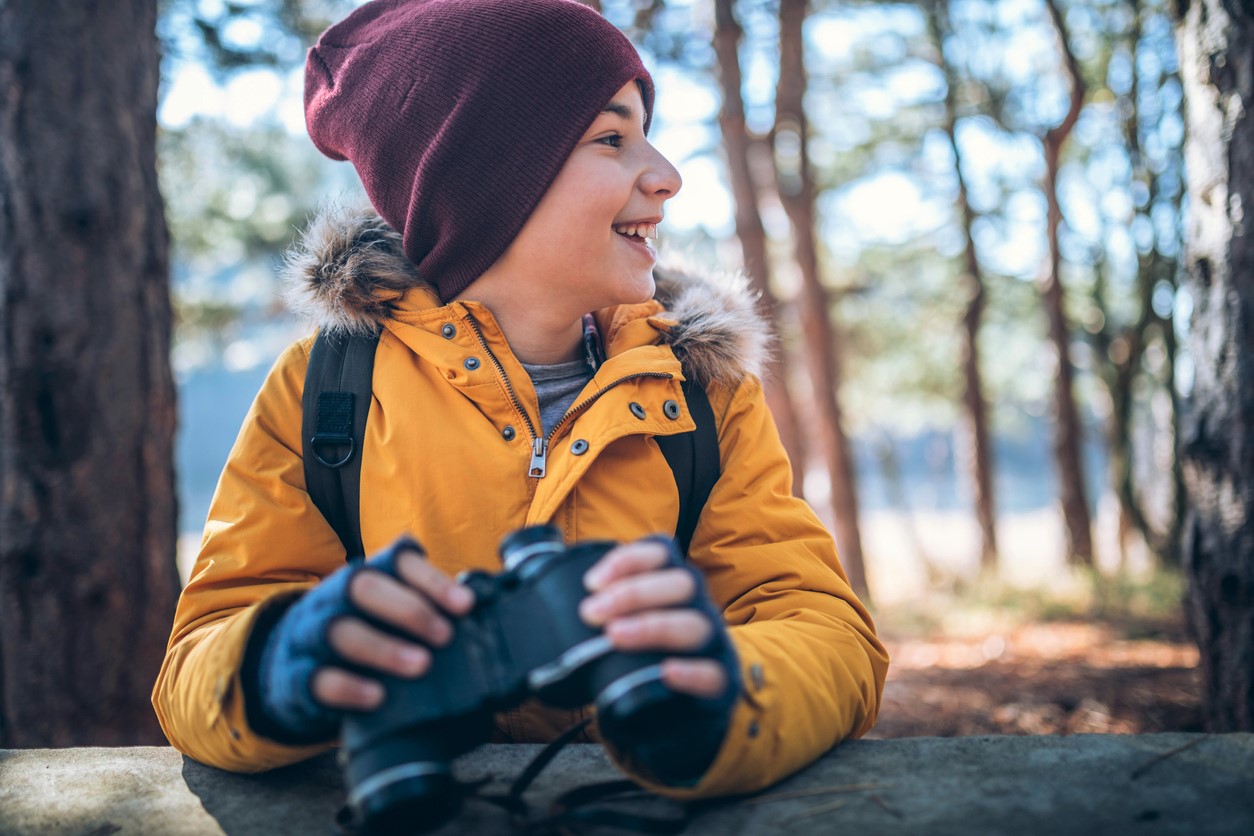 Girl in yellow jacket and hat with binoculars bird watching in Seattle Pacific Northwest