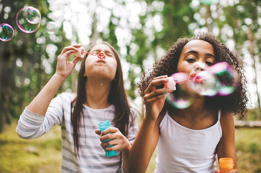 Two girls blowing bubbles outside