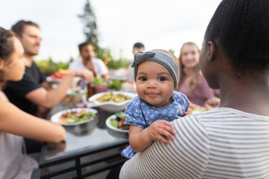 cute baby smiling and looking over mother's shoulder