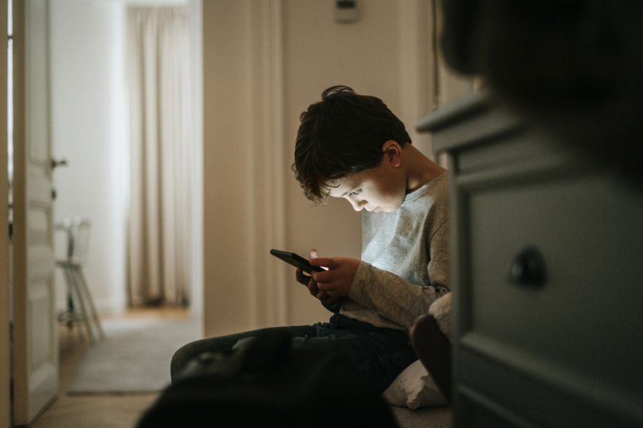 A boy sitting alone looking at a phone the anxious generation