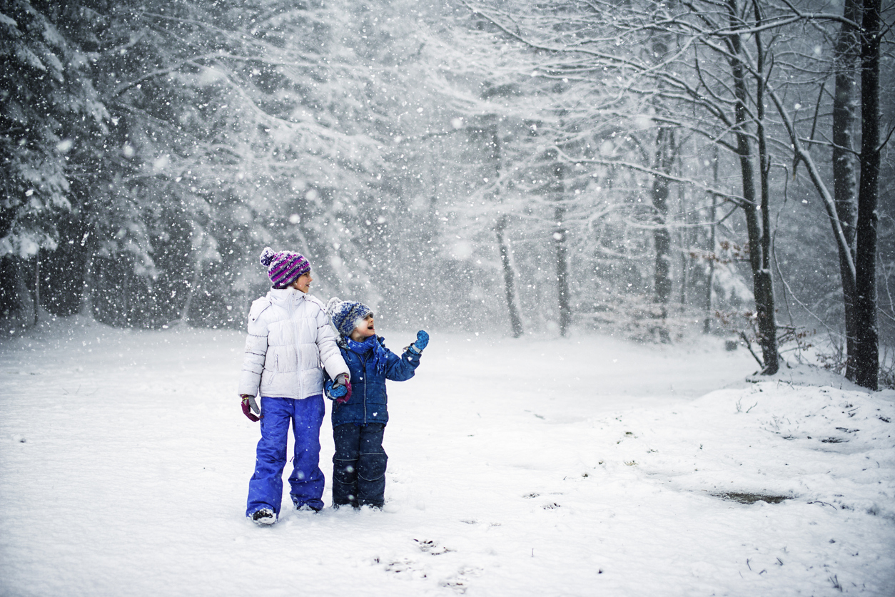 Brother and sister walking in snowy forest