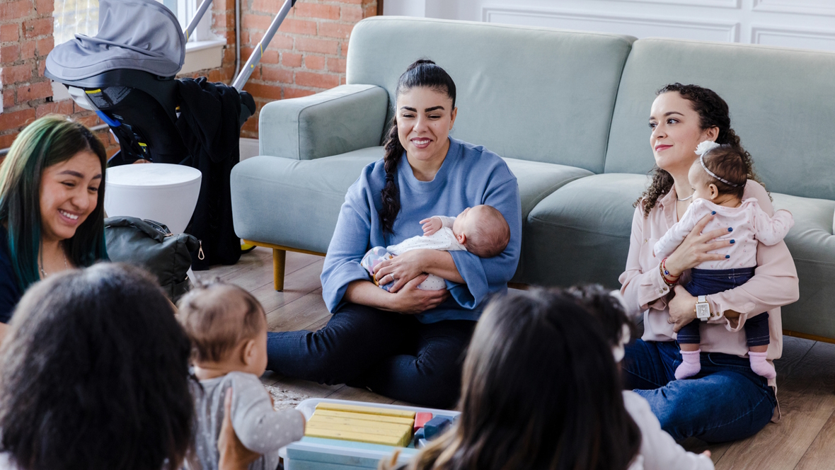 New moms sitting in a living room together connecting as new parents