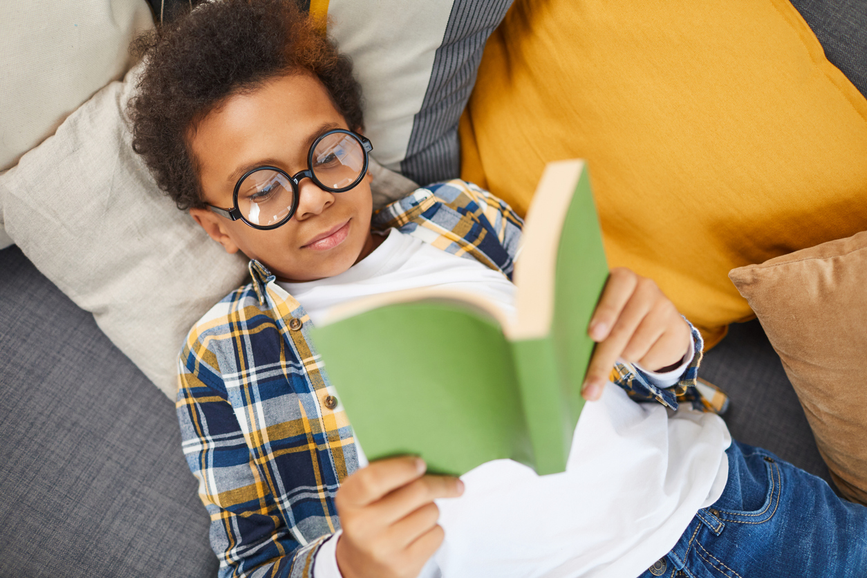 black boy with glasses reading a paperback
