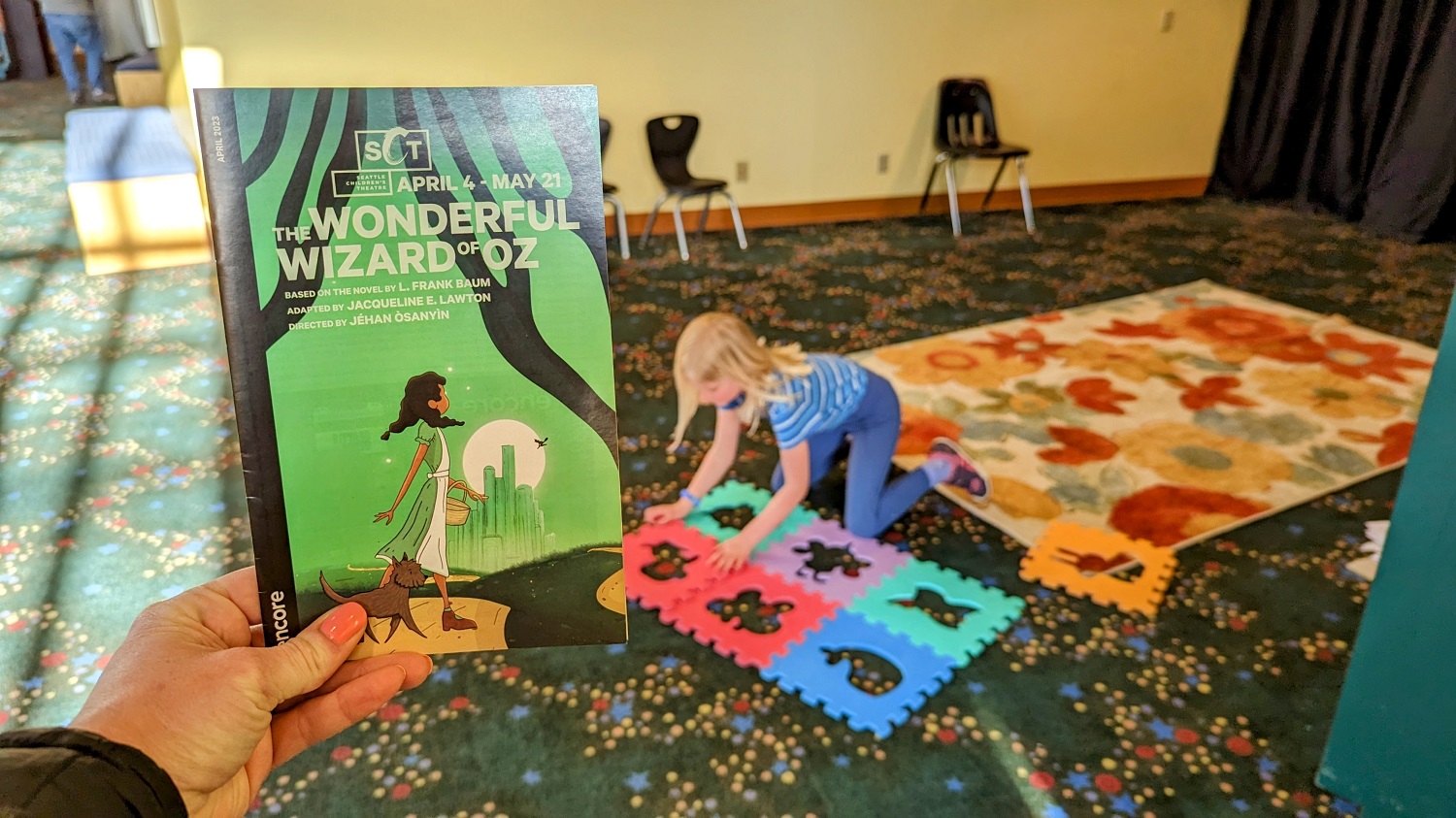 Seattle Children's Theater lobby with child playing and a copy of playbill from the show The Wonderful Wizard of Oz