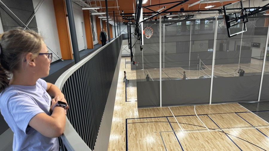 girl watching the sports courts from the second-story track at PenMet rec center