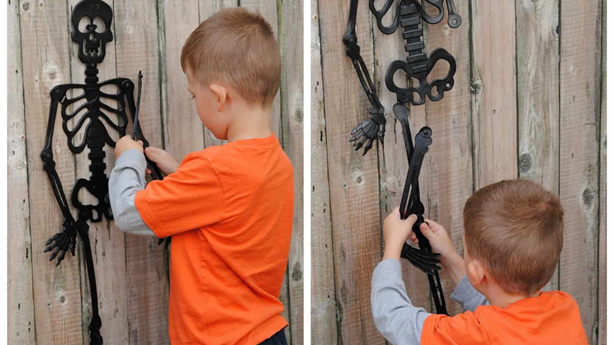 a boy in an orange shirt looking at a black skeleton while playing a Halloween party game