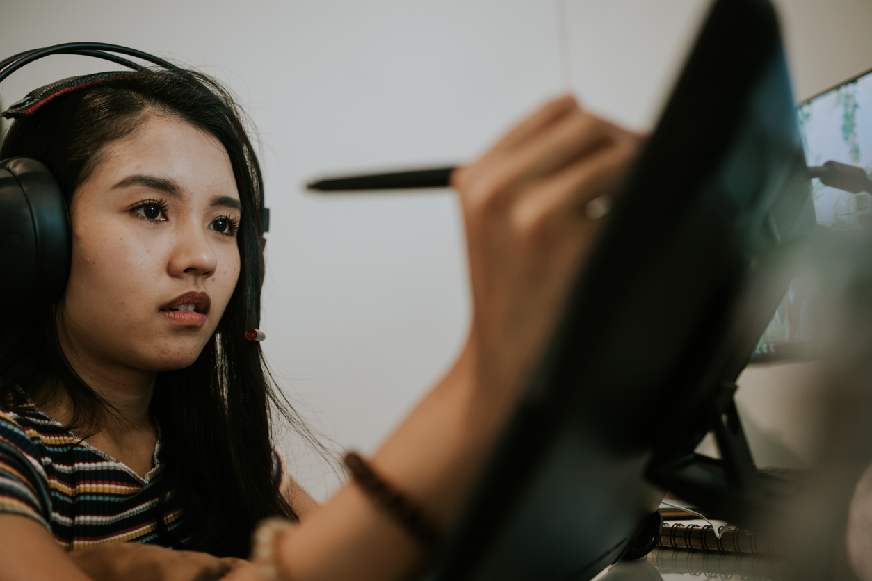 A young Asian woman uses a stylus to create animation on a computer screen