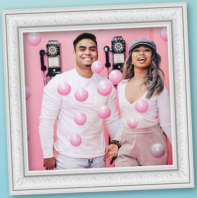 Man and woman taking a selfie with pink balloons in front of them