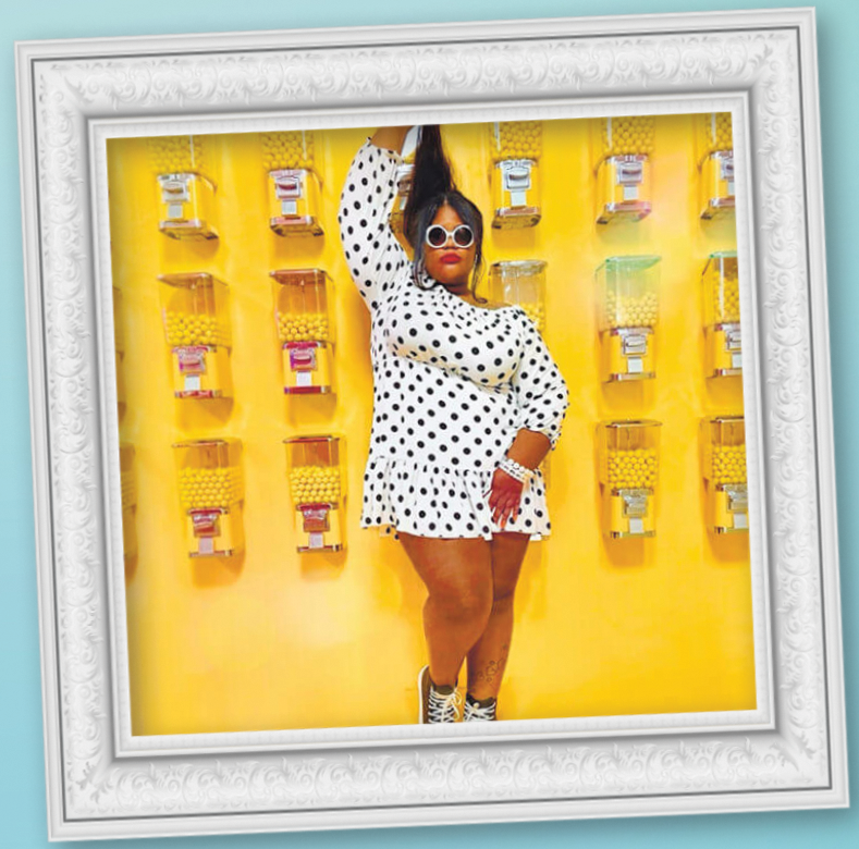 Woman holding her hair up taking a selfie in front of a yellow wall