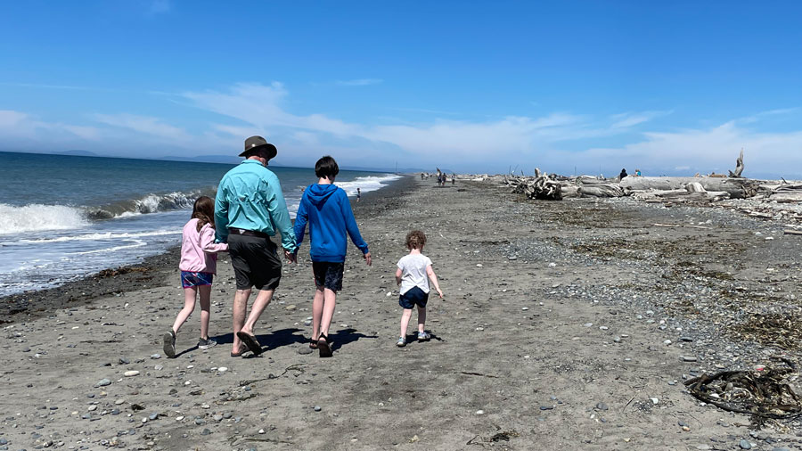 family walking hand in hand along the beach at Dungeness Spit