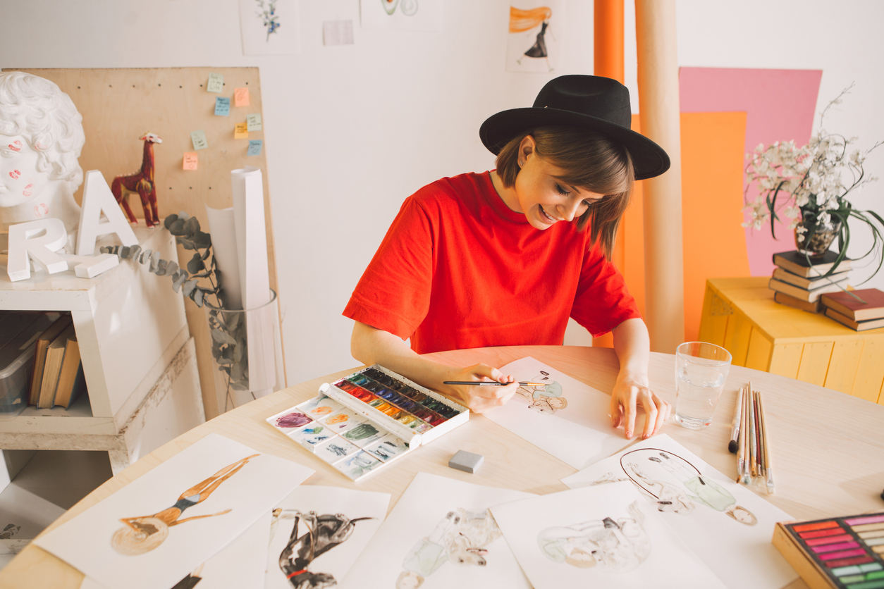 Teen artist wearing a hat painting sketches with watercolors